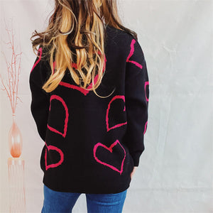 Black acrylic sweater with pink heart outline pattern, crew neck, long sleeves.