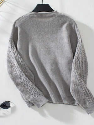 Gray cable knit cardigan with textured sleeves and ribbed cuffs.