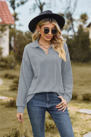 Textured cable knit polo top in light grey with a V-neck and long sleeves.