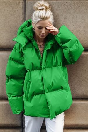 Green oversized puffer jacket with hood and zipper closure, featuring large pockets.
