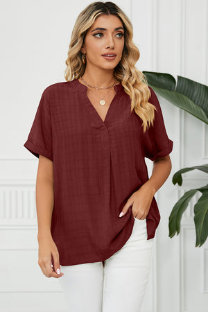 Burgundy blouse with V-neck, rolled short sleeves, and subtle plaid texture.