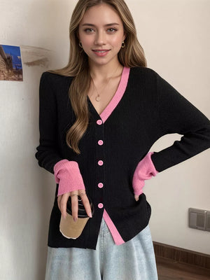 Black ribbed cardigan with pink contrast trim and buttons, long sleeves.