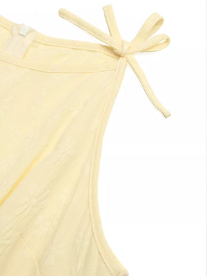 Yellow tie strap jumpsuit with textured fabric and a zipper detail.