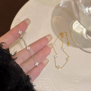 Delicate silver and gold bracelets with four-leaf clover charms.