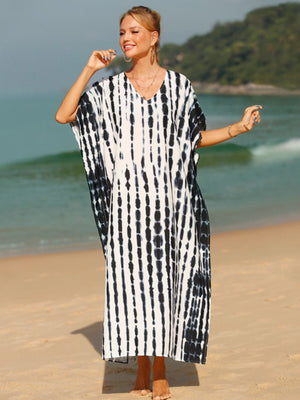 Black tie-dye maxi kaftan dress with vertical stripes and V-neck, worn on the beach.