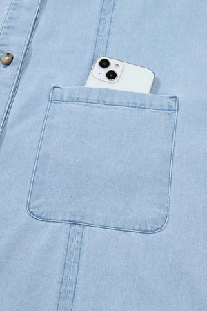 Light blue denim shift dress with button-down front and chest pocket holding a smartphone.