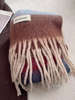 Plush multi-patterned scarf with cream tassels, featuring brown, blue, and red stripes.
