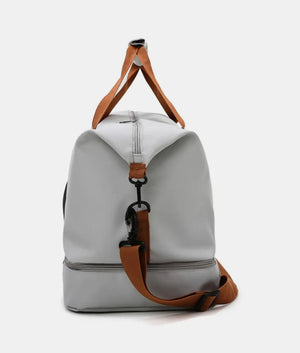 Gray dual-compartment weekender bag with brown contrast straps and hardware.