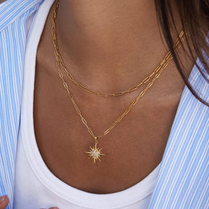 Layered 18k gold necklace with a radiant sun pendant featuring crystal details.