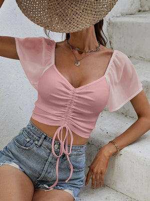 Pink ribbed crop top with sweetheart neckline, adjustable drawstring, and sheer chiffon flutter sleeves.