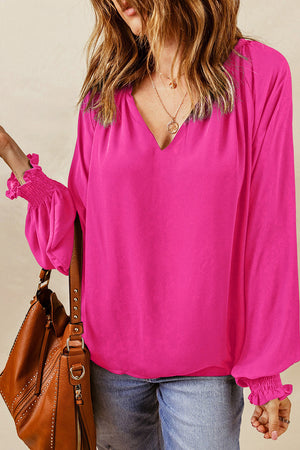 Hot pink blouse with voluminous sleeves and ruched cuffs, V-neckline.