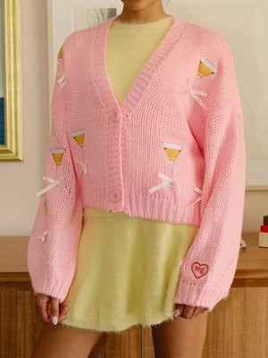 Pink knit cardigan with cocktail glass appliques and bow accents, button-up style.