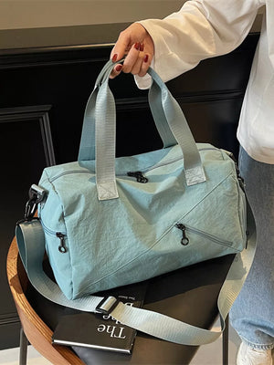 Light blue nylon duffel bag with multiple zippered pockets and adjustable shoulder strap.