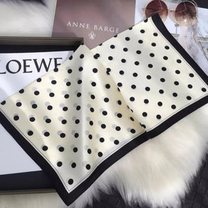 Cream white silk scarf with black polka dots and a black border.