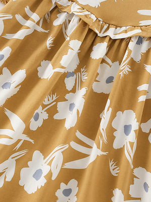 Toddler dress with white floral and bird print on mustard cotton blend, featuring a ruffled neckline.