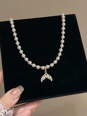 Pearl choker necklace with a delicate mermaid tail pendant adorned with crystals.