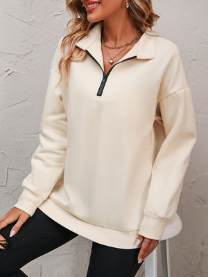 Cream quarter-zip relaxed fit sweatshirt with black zipper detail and ribbed cuffs.