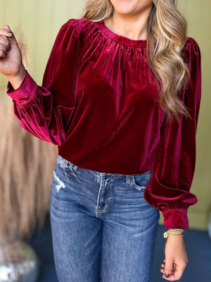 Burgundy velvet long sleeve blouse with ruched neckline and puff sleeves.