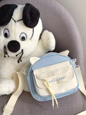 Blue crossbody bag with cat ears and cream flap pocket with embroidery