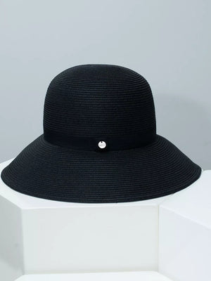 Black straw sun hat with elegant ribbon and silver charm detail.