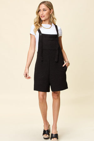 Black textured bib short romper with adjustable straps and pockets