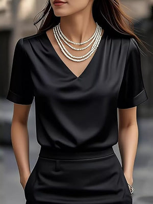 Black satin V-neck shirt with cuffed short sleeves and layered necklace