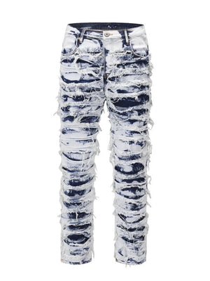 Distressed shredded denim jeans in medium wash with artistic sculptural pattern.