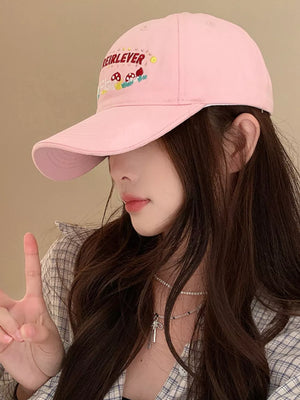 Blush pink baseball cap with playful mushroom embroidery and text detail.