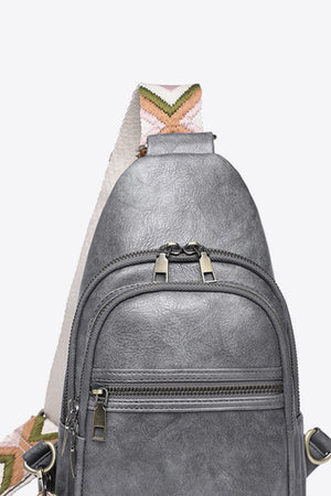 Geometric strap sling bag in Mid Gray with a colorful chevron strap and multiple zippered pockets.