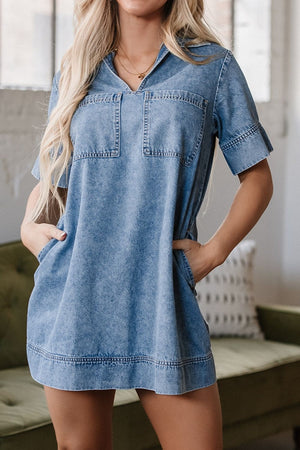 Light blue denim mini dress with short sleeves, a collared neckline, and two chest pockets.