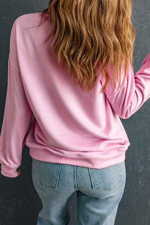 Blush pink crewneck sweatshirt with long sleeves, casual fit, styled with jeans.
