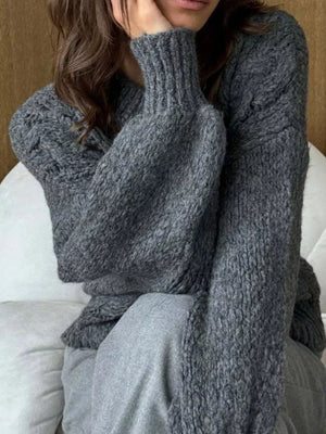 Gray cable-knit cardigan with textured sleeves and ribbed cuffs.
