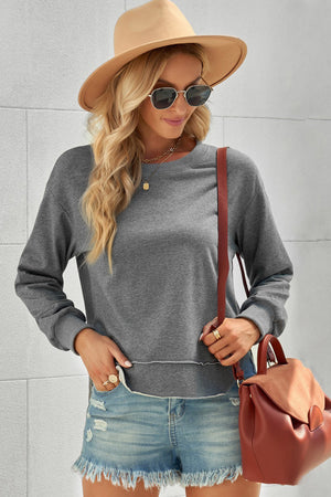 Gray sweatshirt with asymmetric raw hemline, crew neck, and long sleeves.