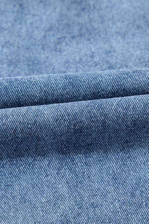 Utility denim mini dress in light blue, showing fabric texture and fold detail.
