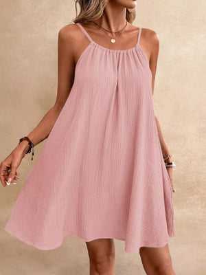Dusty pink spaghetti strap mini dress with gathered neckline and textured fabric.