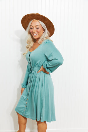 Button-down empire waist mini dress in green with long sleeves and a cinched waist.