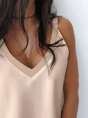 Apricot silky cami top with deep plunge neckline and layered necklaces.