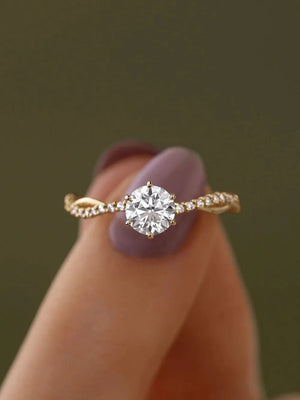 Gold engagement ring with twisted pavé zircon band and solitaire diamond.