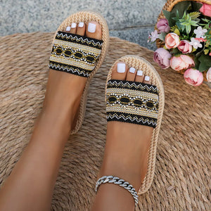 Embossed strap open-toe flat sandals with black and gold woven detail.