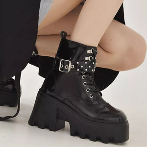 Black glossy platform ankle boots with buckle and stud accents.