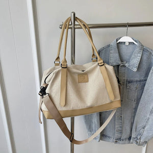 Canvas weekend holdall duffel bag in beige with tan accents and adjustable strap.