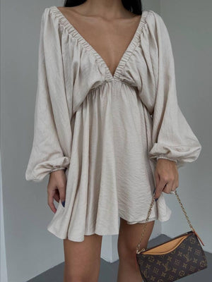 Beige ruched V-neck dress with balloon sleeves and cinched cuffs.