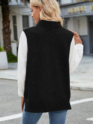 Black cable knit sweater vest with ribbed trim and mock neck, worn over a white shirt.