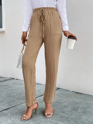 Tan textured tapered trousers with drawstring waist and pockets.