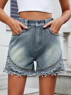 Medium wash denim shorts with studded fringe detail and frayed hem