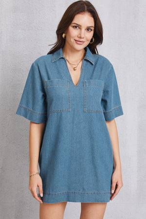 Denim mini dress in medium wash with collared plunging neckline and two chest pockets.