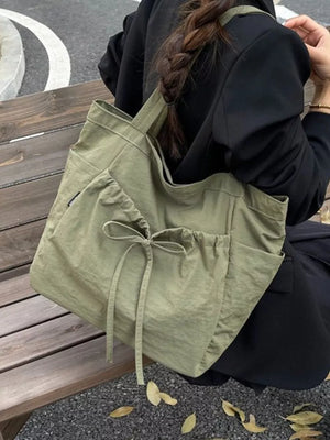 Olive green nylon tote bag with drawstring closure and bow detail.