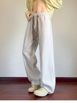 Men's textured wide leg sweatpants in white with a colorful drawstring.