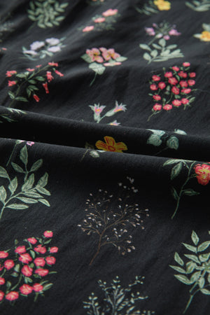 Black cotton blouse with a botanical floral print and short sleeves.
