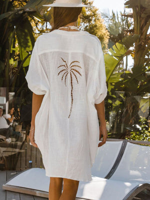 White cotton blend button-down shirt dress with palm tree cutout detail on back.